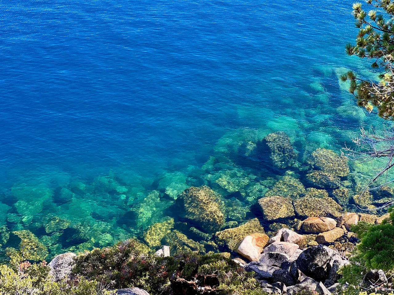 Submerged golden boulders visible through clear blue lake water
