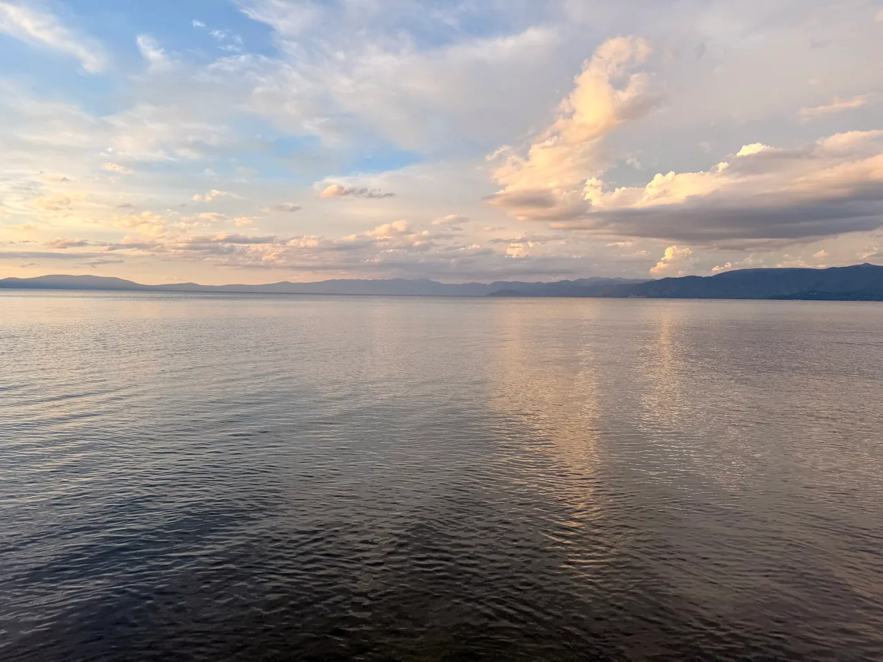 Soft gold clouds reflected in gently rippling lake water