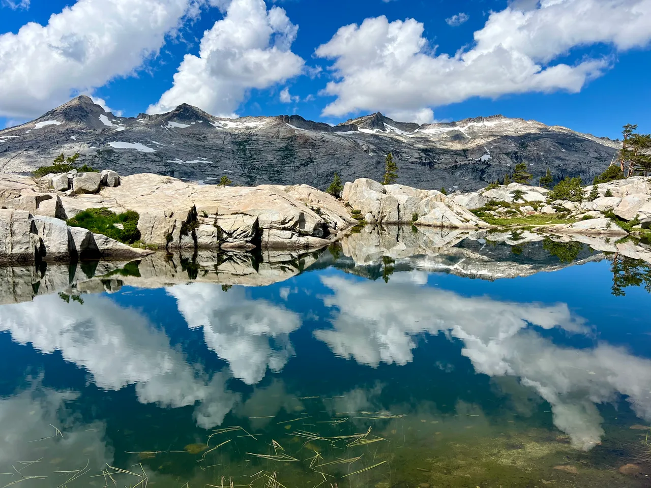 Granite ridges and white clouds mirrored in an alpine lake